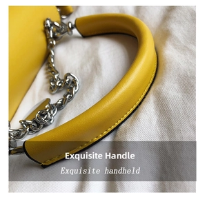 Detail of the bright yellow leather handbag showing the round handle and silver chain link