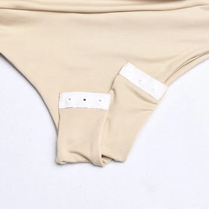 Detailed close-up of the beige bodysuit crotch with white snap fastener closure