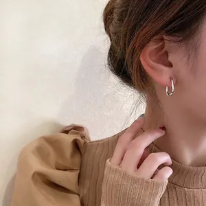 Minimalist silver geometric U-shaped twisted hoop earrings worn by a model