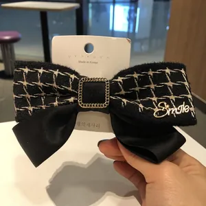 Détail de la grande barrette noeud en satin noir et tweed avec lettrage Smile doré