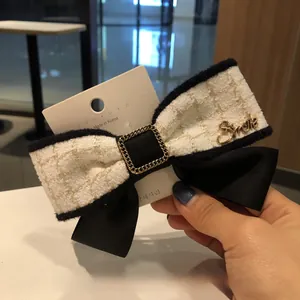 Détail d'une pince à cheveux avec nœud en tweed et lettrage Smile doré élégant