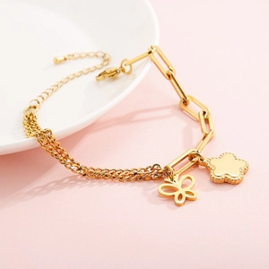 Gold stainless steel bracelet with butterfly and floral charms on an asymmetrical chain