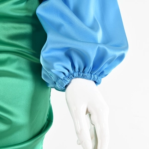 Dettaglio del tessuto satinato con polsino a pieghe in colori blu e verde a contrasto