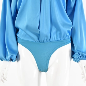 Dettaglio del body blu a maniche lunghe con scollo a V ed elastico in vita su modella