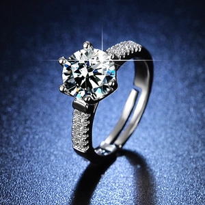 Macro view of six-prong moissanite ring with side stones on a blue matte surface