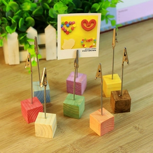 Colorful wooden cube base memo holders with metal alligator clips on a wooden desk