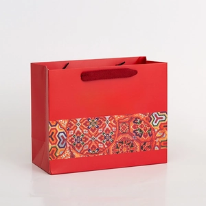 Detail of red paper gift bag with yellow calligraphy and ornate traditional pattern