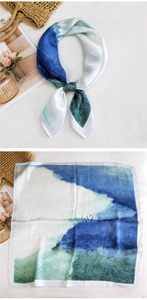 Detail view of a blue and green wave print silk scarf with SEA WAVE text patterns