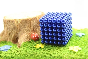 Detailed close-up of blue magnetic balls cube on a miniature green grass moss landscape