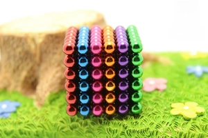 Macro shot of 216 colorful magnetic spheres arranged in a cube on artificial grass
