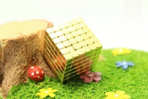 Macro shot of 216 golden magnetic cubes formed into a 6x6x6 cube on a mossy display