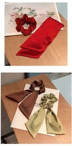 Close-up of elegant satin bow hair ties in burgundy, coffee, and green on wooden desk