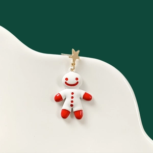 Detailed macro shot of gingerbread man earrings with gold star pendant and red details