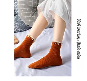 Detailed macro view of orange ribbed socks featuring white lace trim and pearl accents