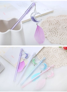 Detail of moon-shaped pens with sequins and feather charms in assorted colors
