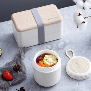 White double-layer bento box and thermal cup set with wood grain lids on a grey table