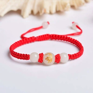 Close-up of handmade red string bracelet with glowing beads and golden zodiac tiger charm