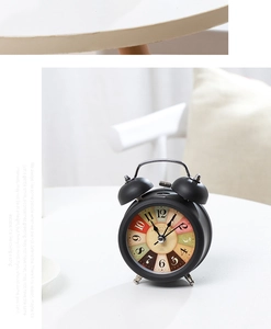 Detail of 3-inch vintage black metal twin bell alarm clock with retro Paris dial on desk