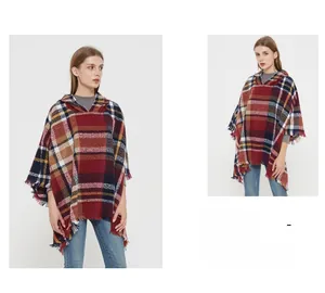 Detail of red and blue plaid hooded poncho featuring long tassel trim and cozy texture