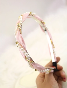 Detail of pink fabric headband with faux pearls and golden rhinestones in macro view