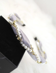 Close-up of lilac twisted fabric headband with white faux pearls and gold rhinestones
