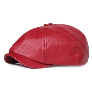 Side view of a vintage red leather newsboy cap with a classic stitched crown and button top