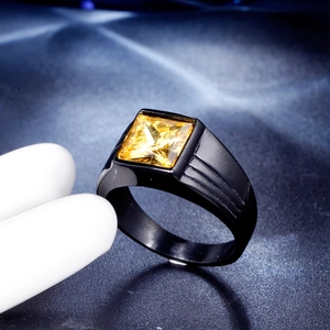 Detail of men's titanium ring featuring square yellow gemstone on white hand model