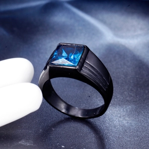 Detail of square blue gemstone set in a black stainless steel mens ring on silk background