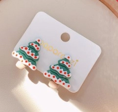 Detail shot of resin Christmas tree earrings with festive red dots on a display card