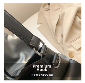 Detail of silver metal hook and leather strap connection on black spring tote bag
