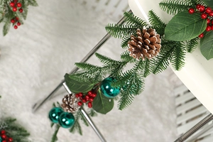 Macro detail of Christmas garland featuring pine cones, red berries and green ornaments