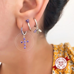 Close-up of S925 sterling silver earrings set with purple zircon cross charms on ear