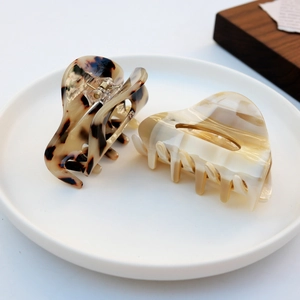 Minimalist acetate hair claw clips in tortoiseshell and marble patterns on ceramic tray