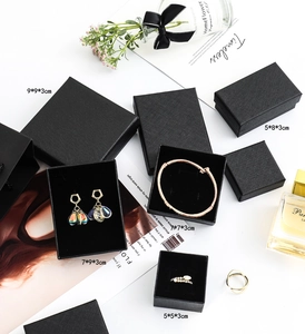 Flache Ansicht schwarzer strukturierter Schmuck-Geschenkboxen mit Ringen und Trockenblumen