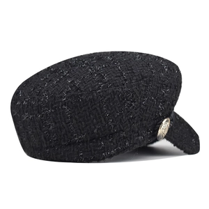 Side view of a premium black tweed baker boy hat featuring a decorative gold button.