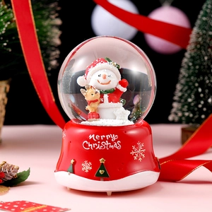 Close-up of Christmas crystal ball with snowman and reindeer on red Merry Christmas base