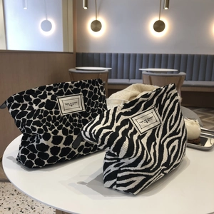 Canvas makeup bags with black and white animal prints on a cafe table with zipper closure