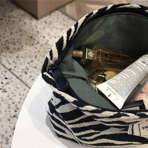 Interior view of spacious zebra print canvas makeup bag with black zipper and inner lining