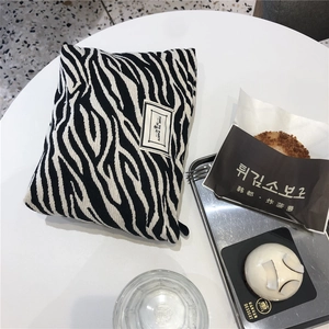 Detailed close-up of a zebra print canvas pouch with a Time to Party woven label