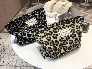 Close-up of leopard print canvas makeup bags with Time To Party labels and black zippers