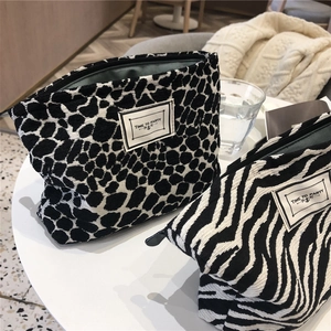 Close-up of leopard and zebra print canvas makeup bags on a white table in a cafe