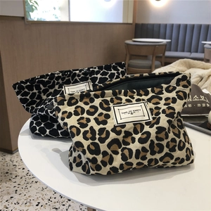 Detail of canvas leopard print makeup bags with zipper closure on a white cafe table