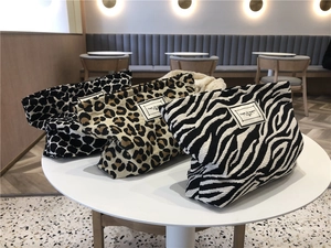 Detailed close-up of canvas leopard and zebra print cosmetic bags on a white table