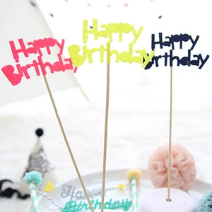 Close-up of red yellow and black Happy Birthday cake toppers with wooden sticks