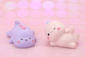 Cute pink and purple dinosaur cake toppers made of resin on a pink sequin background