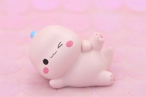 Macro detail of a cute pink dinosaur cake topper with blue horns and heart-shaped paws