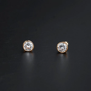 Vue détaillée de boucles d'oreilles dorées rondes avec zircons sur fond noir élégant