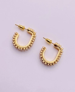 Macro shot of gold-plated U-shaped earrings with micro-paved white cubic zirconia stones