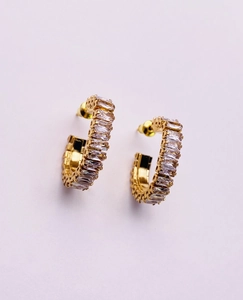 Macro view of gold C-shaped earrings with square-cut cubic zirconia in a French style