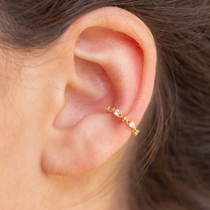 Macro shot of gold ear cuff with hollow geometric texture and sparkling cubic zirconia